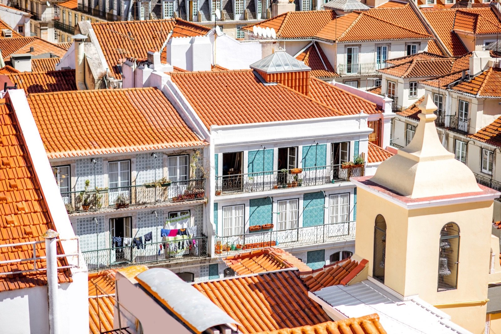 Prédios de habitação de Lisboa com telhados de telha e varandas com roupa estendida.