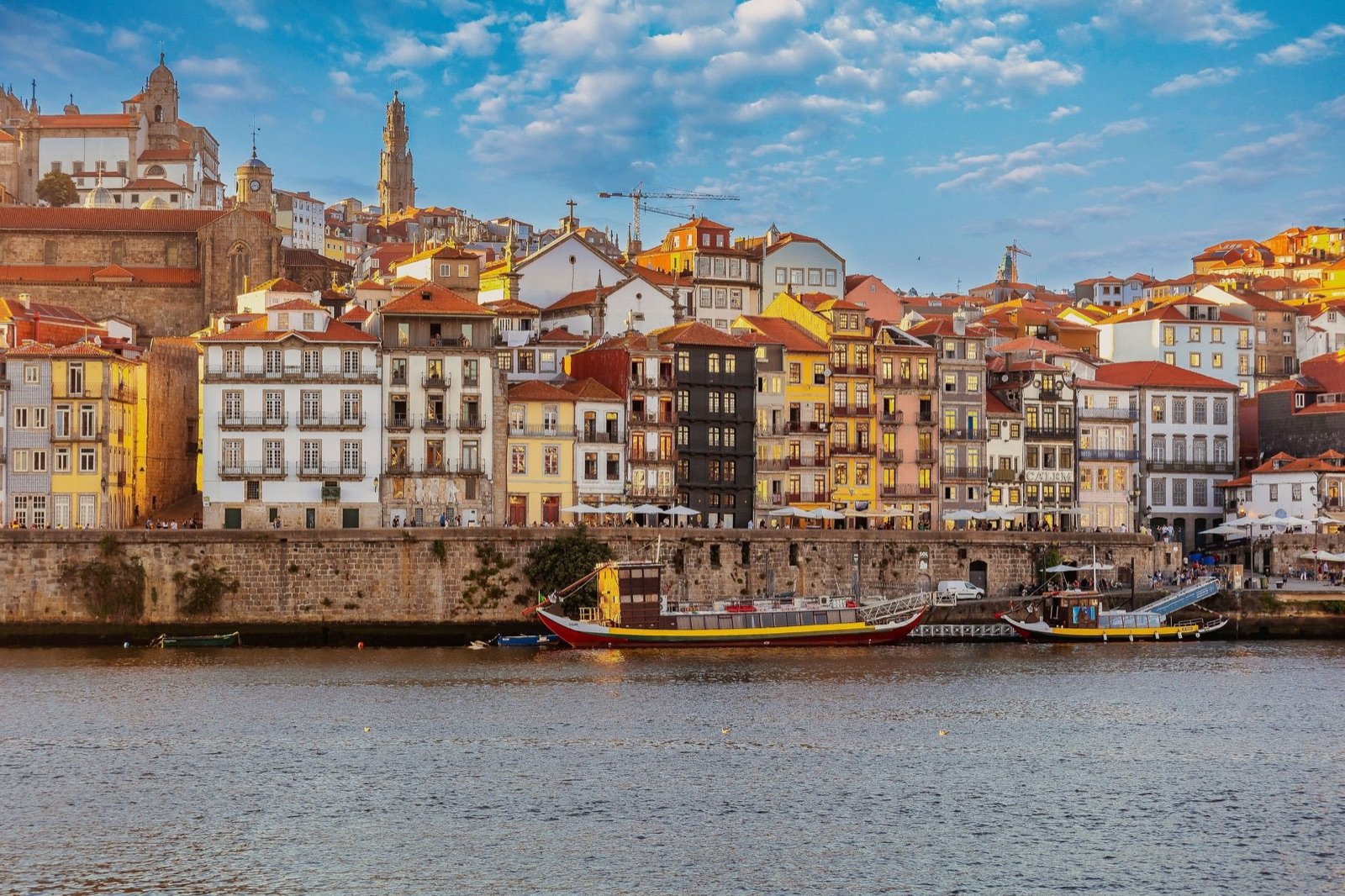 Casario antigo e colorido da Ribeira do Porto, junto ao rio Douro, com barcos rabelos atracados.